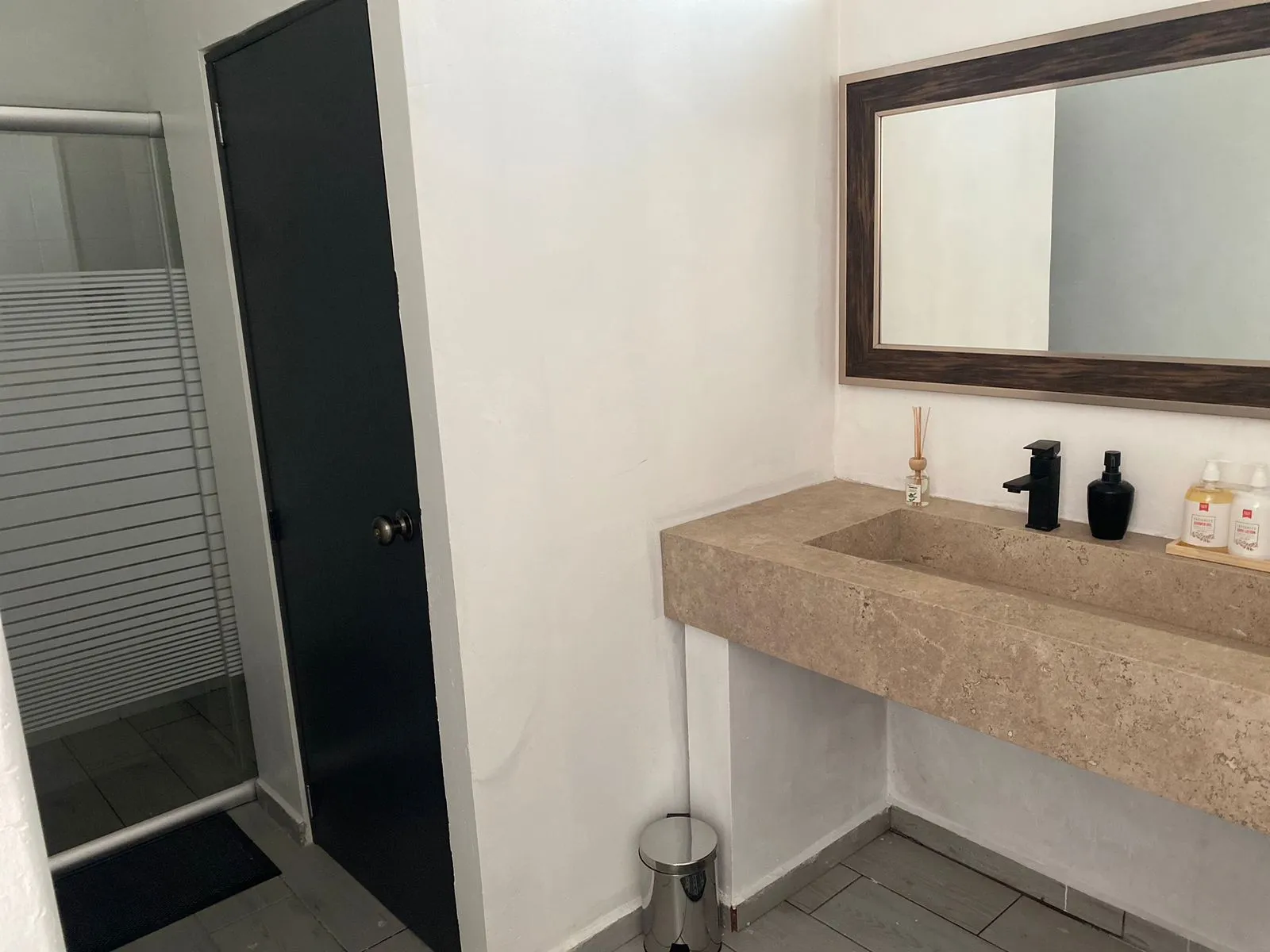 Baño con tocador de piedra y regadera de vidrio