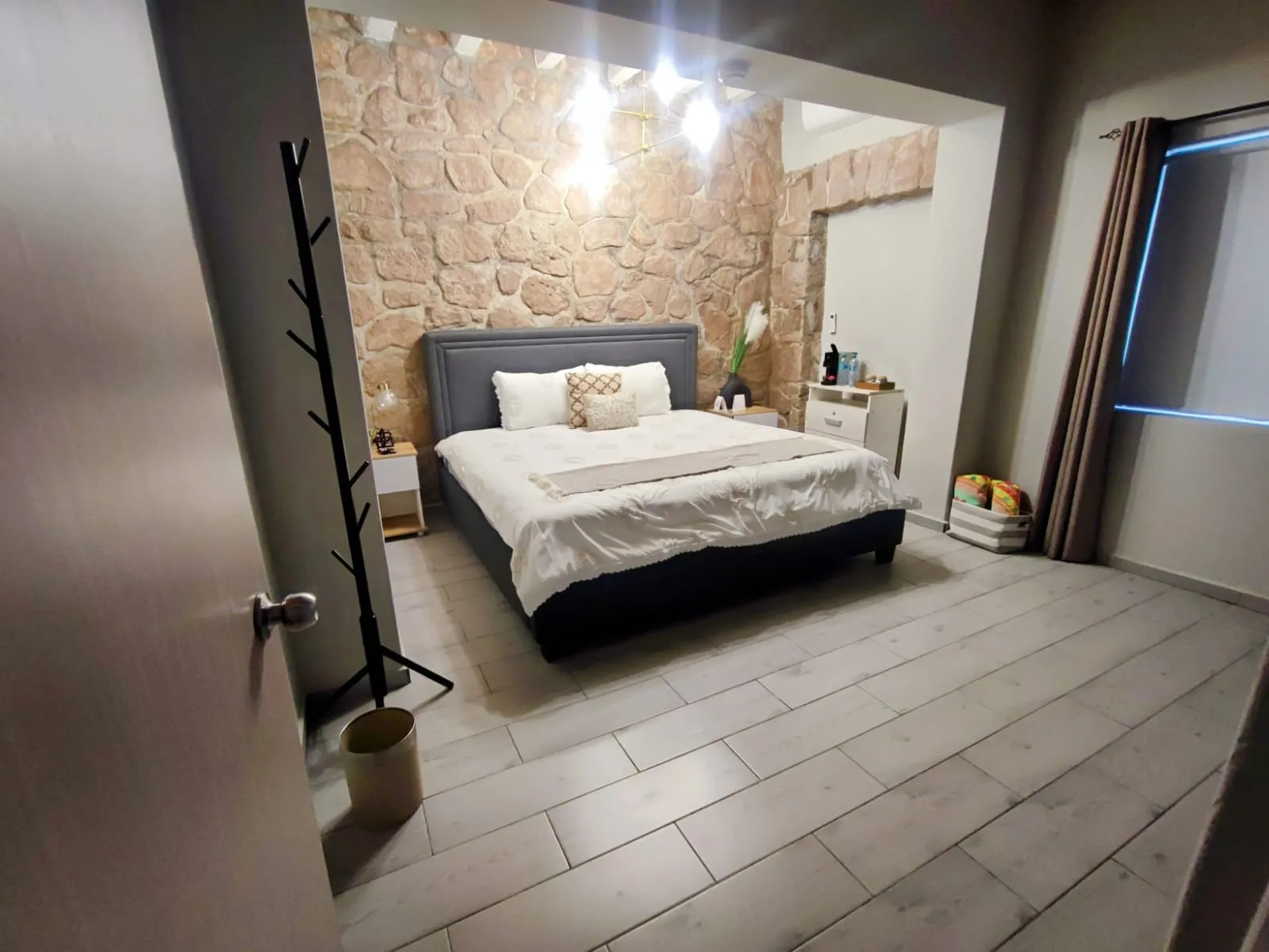 Recámara con cama king size y pared de piedra, vista desde la entrada