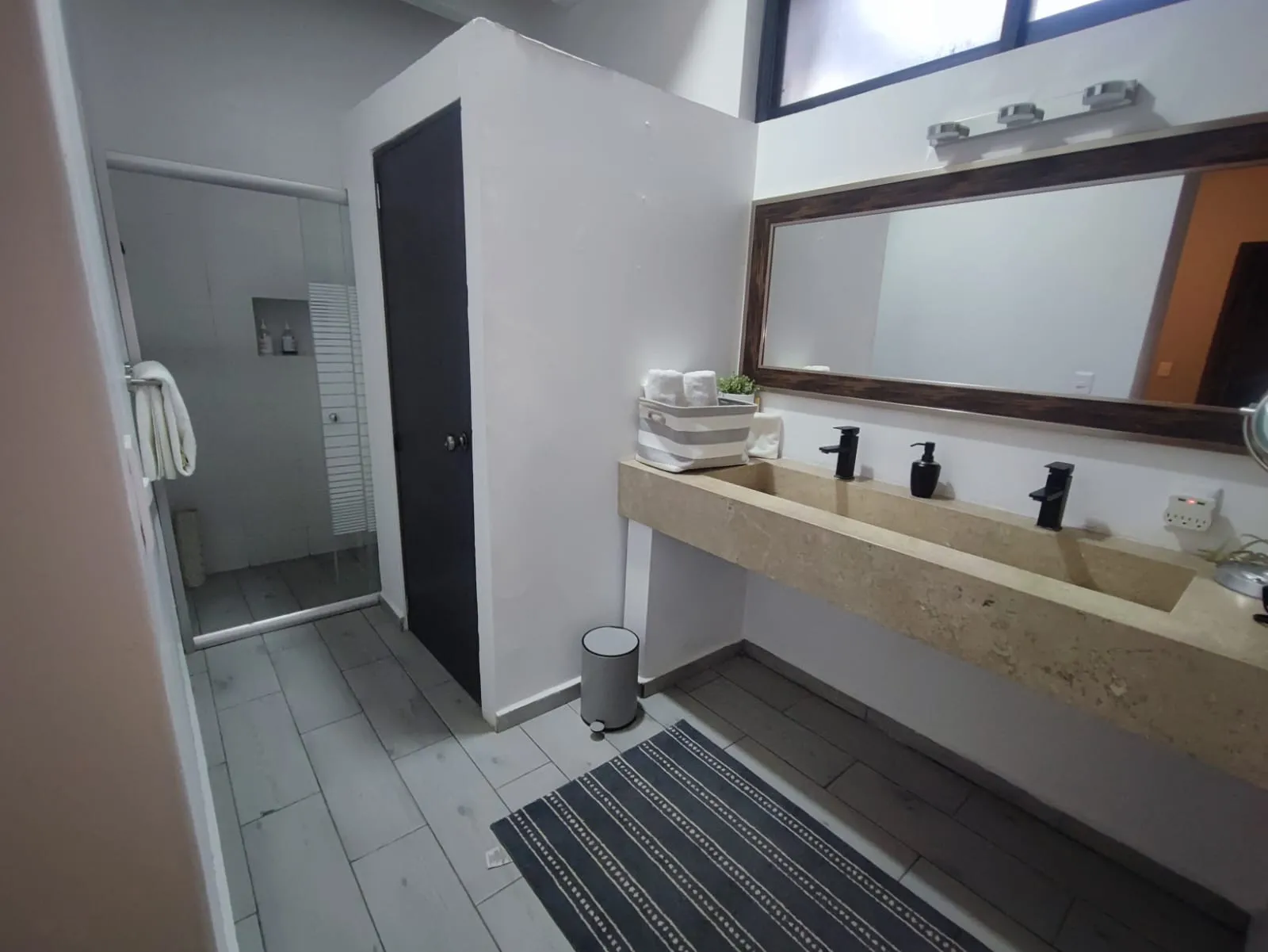 Baño con tocador de piedra en forma de U y regadera de vidrio