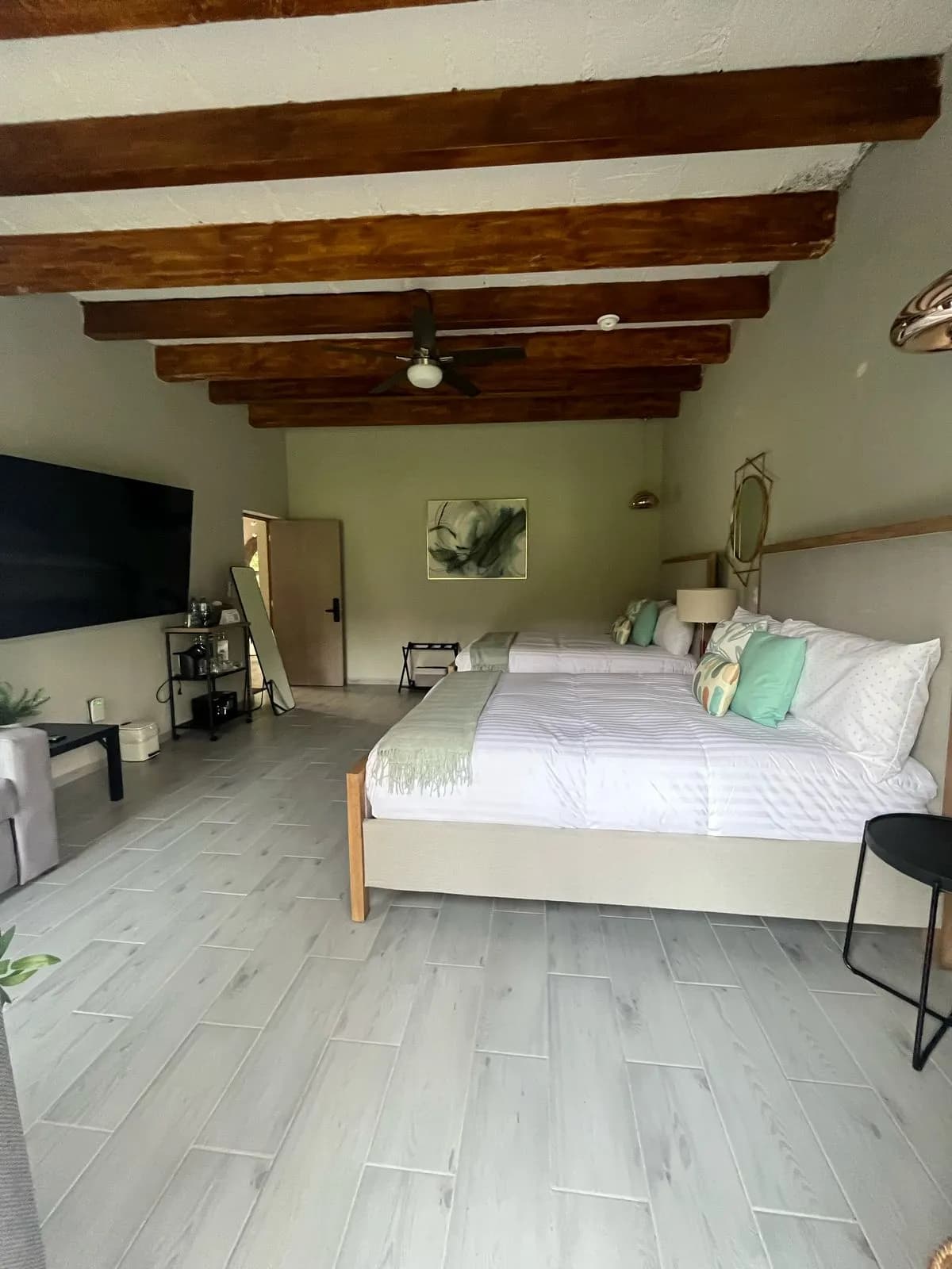 Recámara con TV, sala y techo de vigas de madera