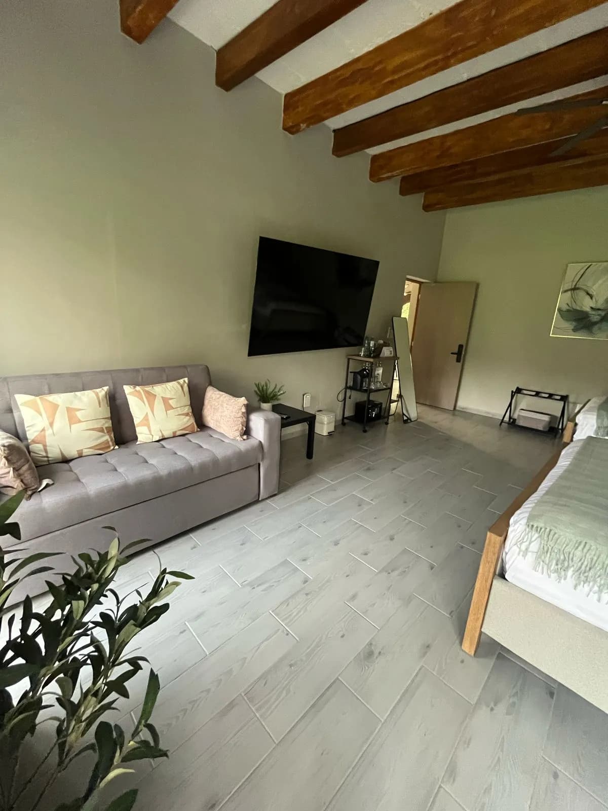 Sala de estar con sofá, TV y techo de vigas de madera