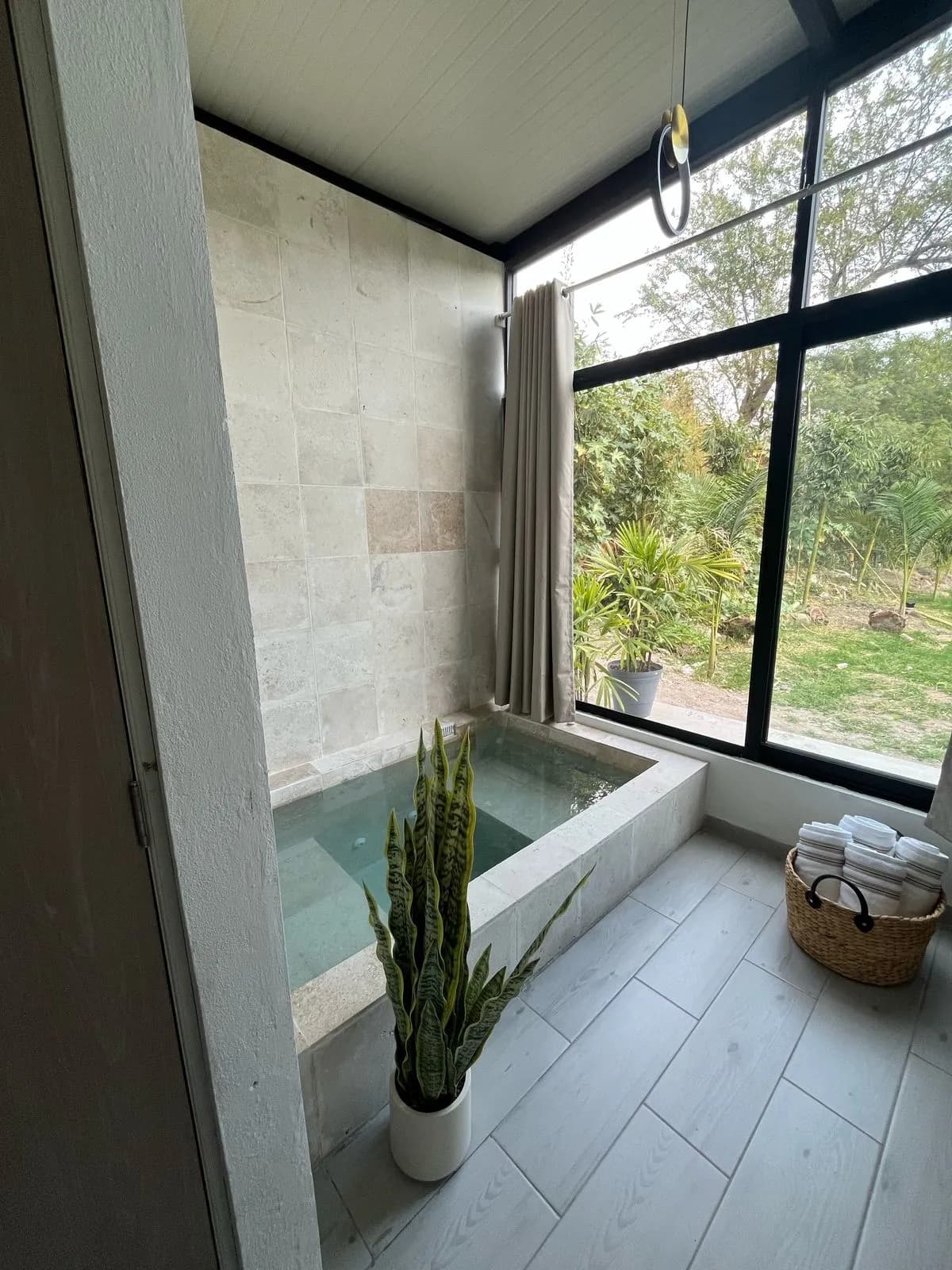 Jacuzzi privado de piedra junto a un ventanal con vista al jardín