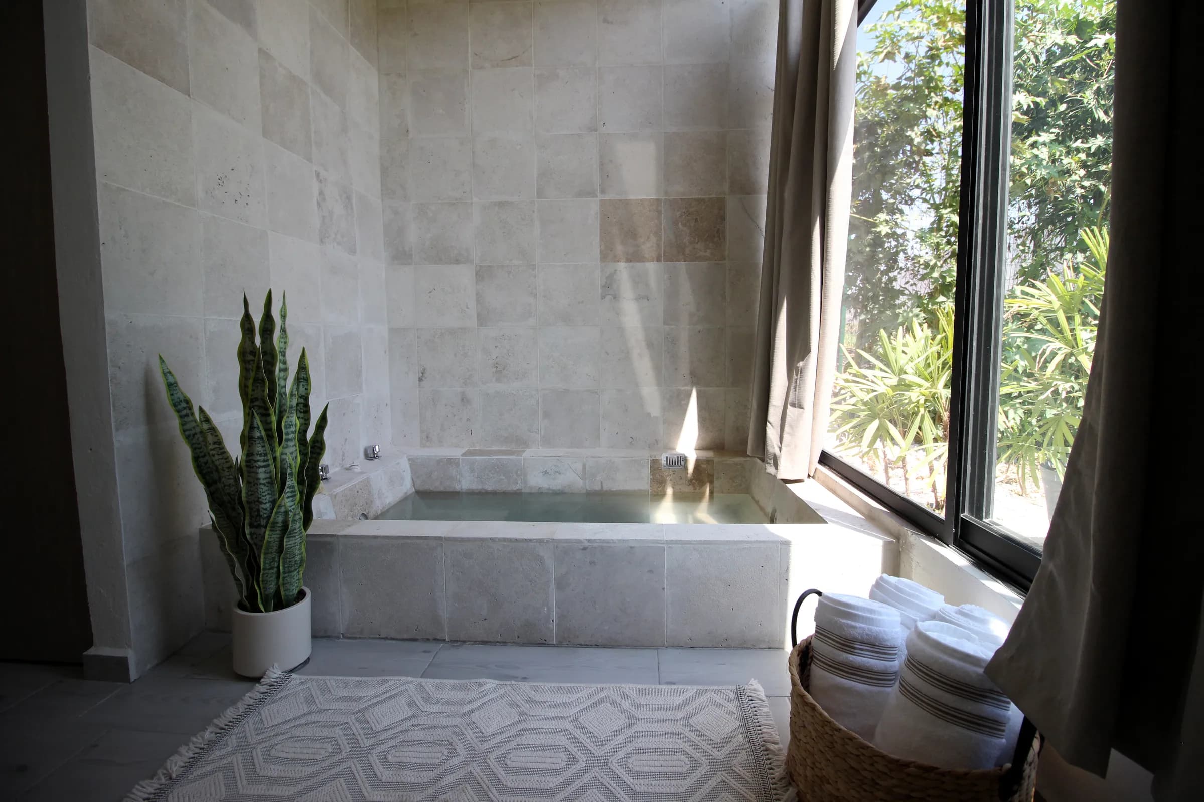 Jacuzzi privado de piedra con vista al jardín en una suite de Casa Laureles