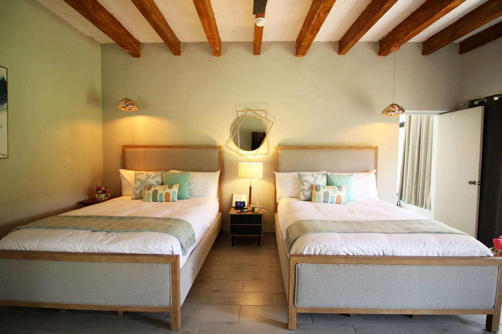 Recámara con dos camas y decoración en tonos verdes en una suite Casa Laureles